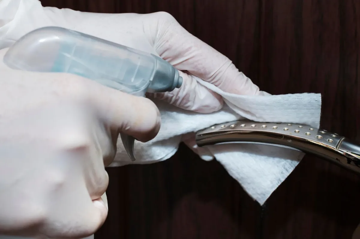 Hands with gloves disinfecting a door handle